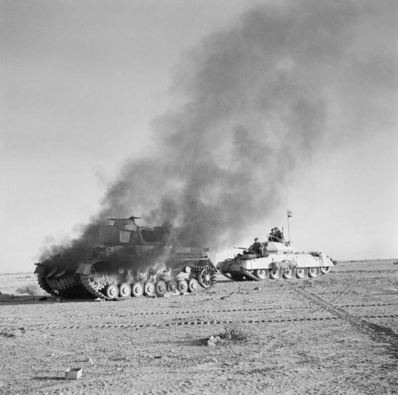 Britischer Crusader Panzer fährt an brennendem Panzer IV vorbei
